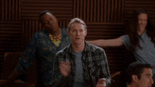 a group of people are dancing in a room with a wooden wall behind them
