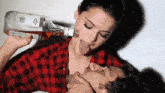 a woman in a plaid shirt is drinking from a bottle of ketel one