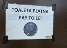 a sign that says toaleta platna pay toilet is taped to a brown wall