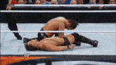 two men are wrestling in a ring with a w logo on the bottom right