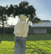 a person wearing a yellow hoodie is standing in a park