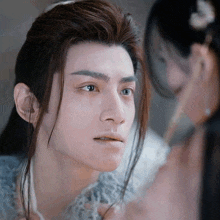 a close up of a man 's face with a woman behind him