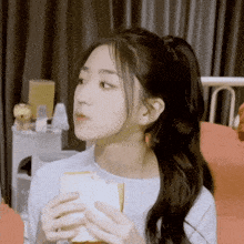 a woman is holding a piece of bread in her hand and looking at it .