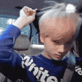 a young boy is putting his hair in a bun while sitting in a car .
