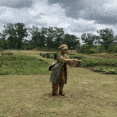 a statue of a woman standing in a field with trees in the background and a cloudy sky