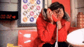 a woman in a red jacket is sitting at a table talking on a red phone .