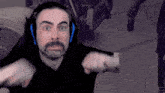 a man with a beard is wearing headphones and making a funny face while playing a video game .