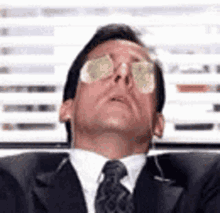 a man in a suit and tie is wearing sunglasses and looking up at the sky .