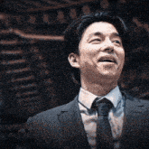 a man in a suit and tie is smiling in front of a staircase .