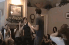 a group of people are dancing in a living room in front of a fireplace .