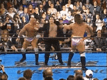 a group of men are standing in a wrestling ring with a referee .
