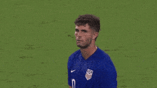 a man in a blue shirt is standing on a field with his eyes closed