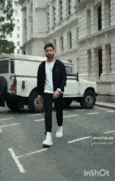 a man walking down a street in front of a white vehicle