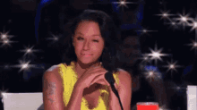 a woman in a yellow dress is sitting in front of a microphone and making a funny face .