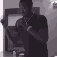 a man in a black shirt is standing in front of a mirror in a room .