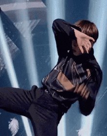 a man in a plaid shirt and black pants is dancing on stage .
