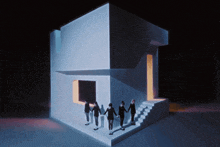 a group of people are holding hands in front of a white building