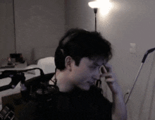 a man wearing headphones is sitting in a dark room with a lamp .