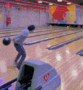 a man throws a bowling ball in a bowling alley with a sticker that says q on it