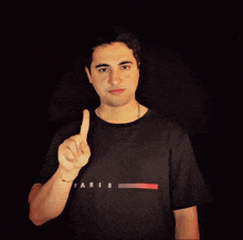 a man wearing a paris t-shirt points up