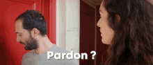 a man and a woman are standing in front of a red door with the words pardon written on the bottom