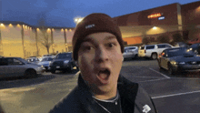 a man wearing a beanie that says obey is standing in a parking lot