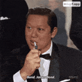 a man in a tuxedo is lighting a cigarette and saying bond james bond