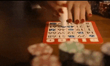 a person with red nails is playing a game of bingo on a table
