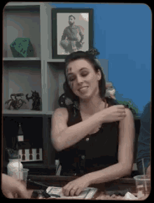 a woman sitting at a table with a picture of a man behind her