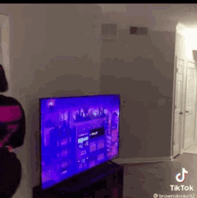 a woman is standing in front of a tv with a purple screen
