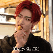 a man with red hair is eating food and the name ricky de abi is on the bottom right