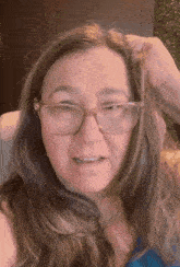 a woman wearing glasses is scratching her head with her hand