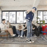 a group of young men are sitting on a couch in a living room while a man is dancing .