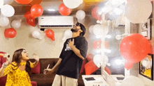 a man and a woman are dancing in a room with balloons on the ceiling .