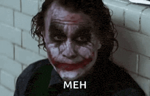 a close up of the joker 's face with a smiley face and the words `` meh '' written below him .