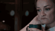 a woman is holding a cup of coffee and making a sad face