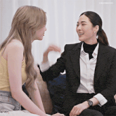 two women are sitting on a couch and one has a watch on her arm