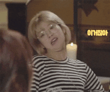 a woman wearing glasses and a striped shirt is making a face .