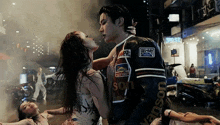 a man wearing a jacket that says son on it kisses a woman