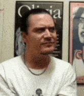 a man wearing a white shirt is standing in front of a poster that says " olivia "
