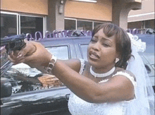 a woman in a wedding dress is pointing a gun at someone