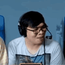 a man wearing headphones and glasses is sitting at a table with a microphone .