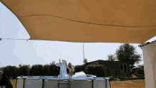 a unicorn float sits on top of a swimming pool under a canopy