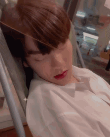 a man in a white shirt is sleeping in a chair with his eyes closed