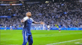 a man is standing on a soccer field with his arms outstretched