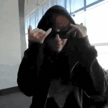a person wearing a black hoodie and sunglasses is making a funny face