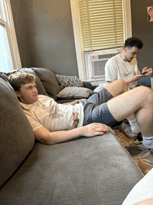 a man wearing a nike shirt sits on a couch with his legs crossed
