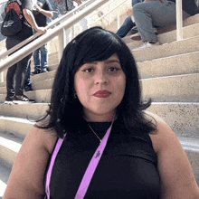 a woman wearing a lanyard that says ' a ' on it sits on a set of stairs