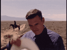 a man in a blue shirt is holding a cowboy hat