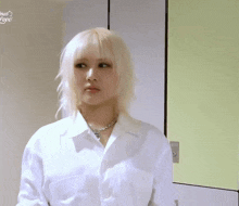 a woman with blonde hair is wearing a white shirt and a silver necklace